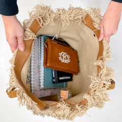An over the top view of the inside of the large tote bag purse. Shows the large and open compartment, with many note books, books, a water bottle, a purse and organizing pouch inside.