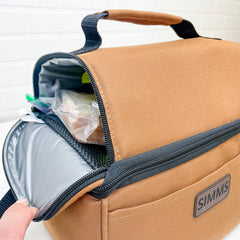 Interior of Lunch Box. Top zippered compartment for sandwiches and chips. Shows capacity of six bottles (horizontally) and up to 10-12 oz cans. A lunch packed with sandwich and chips in the top compartment. Drinks, pickles and apple in bottom.